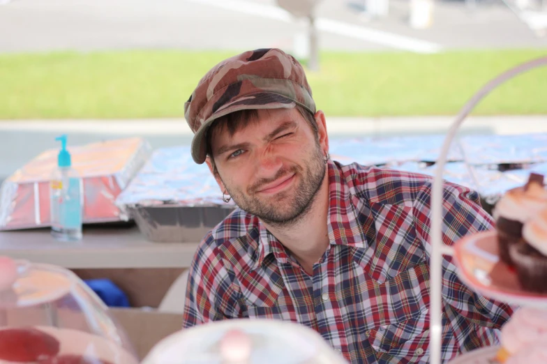 man sitting next to several cup cakes in bowls