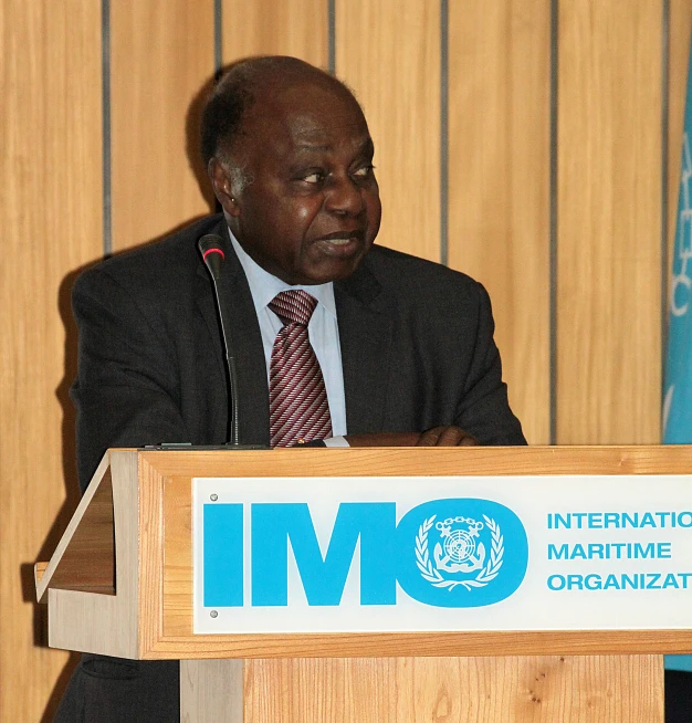 a man in suit and tie standing at a podium with a microphone