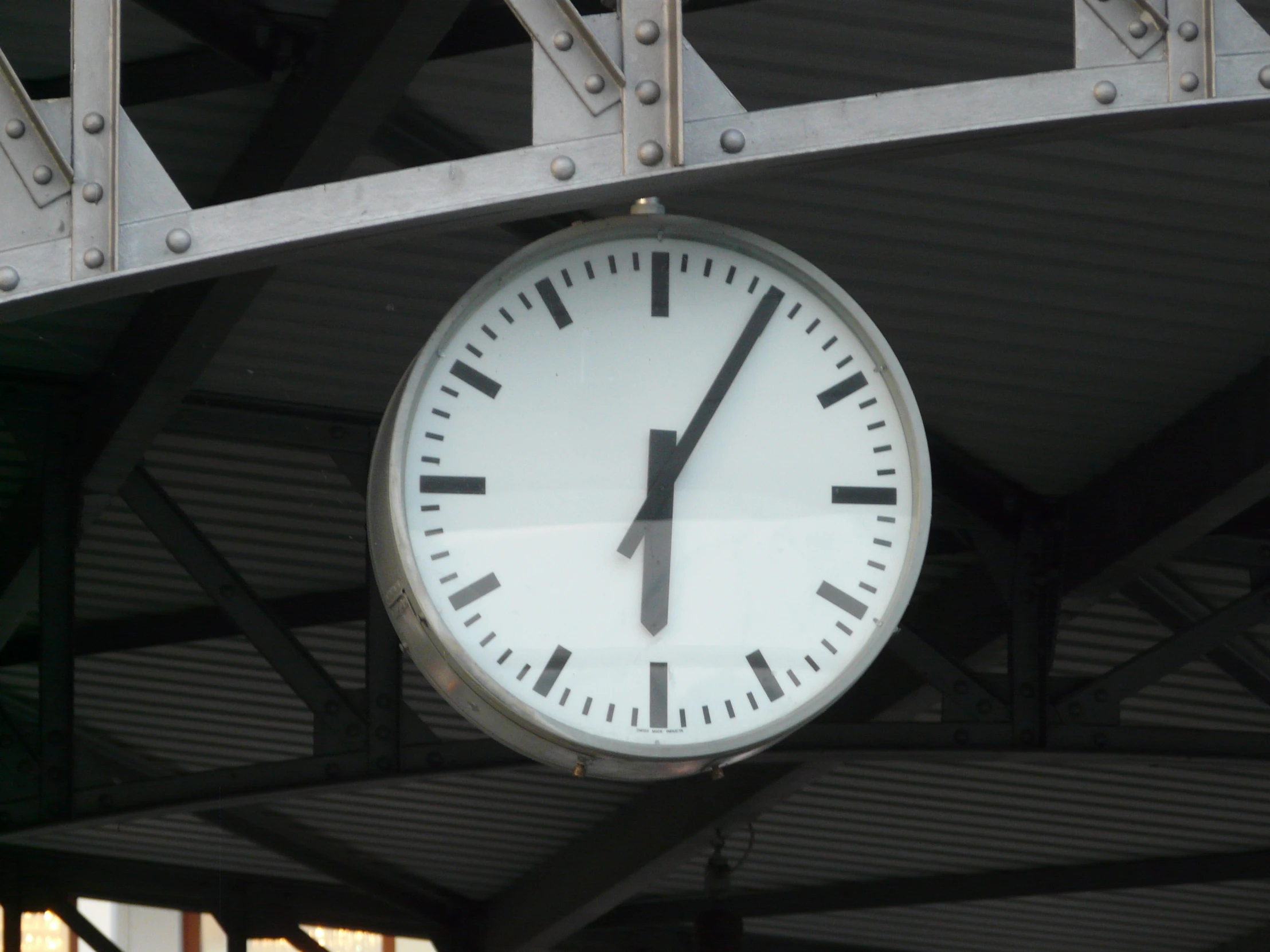 the clock is hanging from the roof of a building