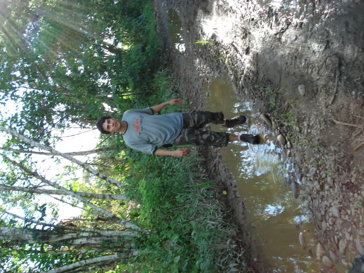 a young man leaning against a tree near the river