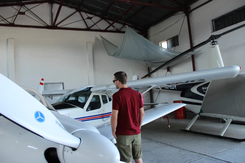 a young man standing next to an airplane in a hangar