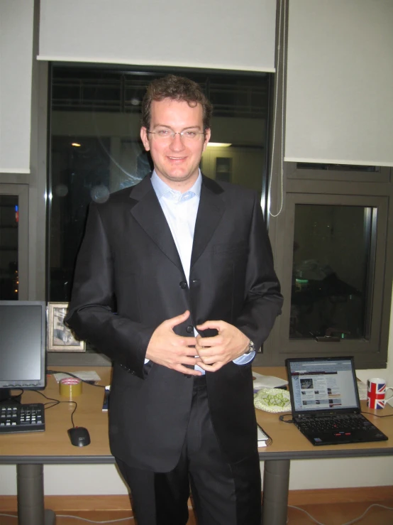 a man in a suit stands next to two laptops