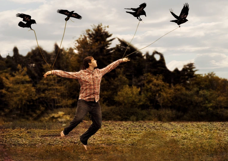 a young man runs through a field with several birds that are flying in the sky