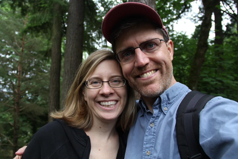 a man and woman standing by some trees