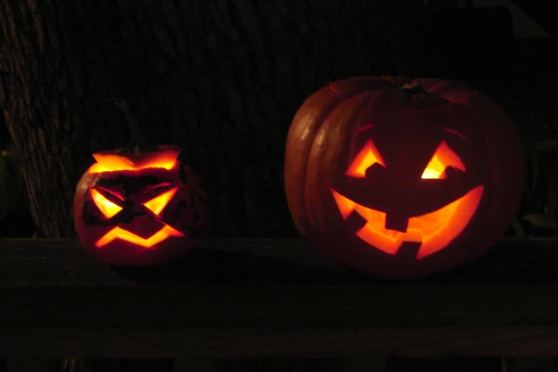 two carved jack - o'- lanterns with faces in the dark