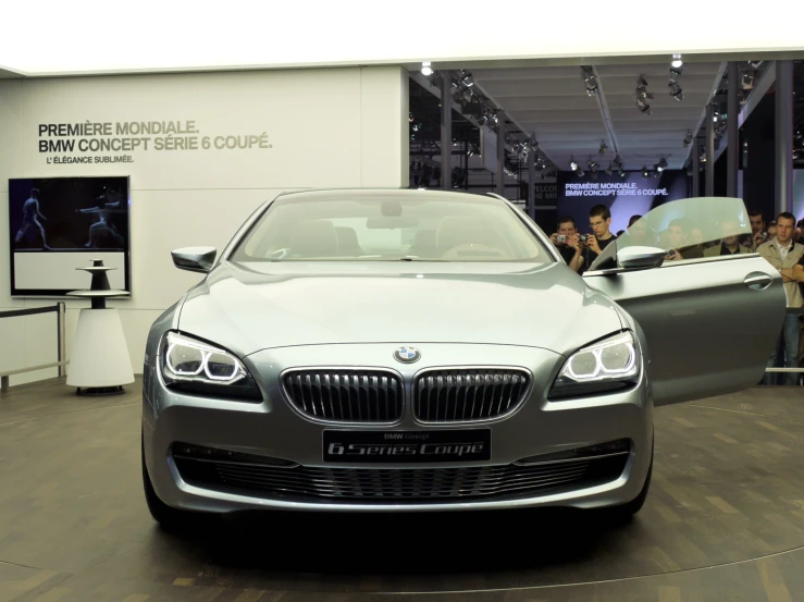 the front end of a silver bmw car on display at a show