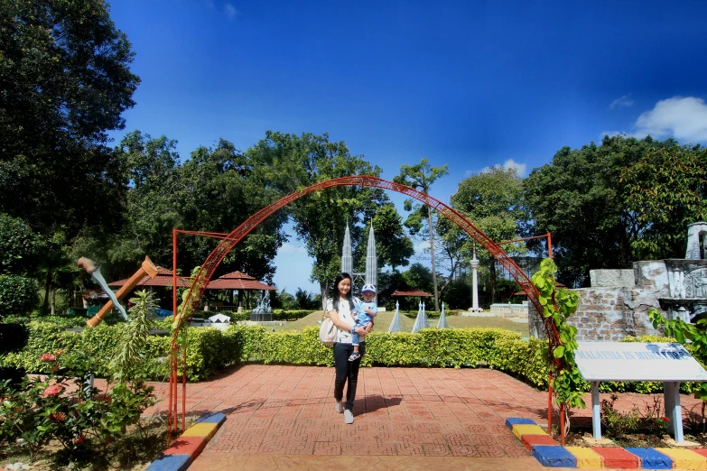 a woman stands in front of a garden archway