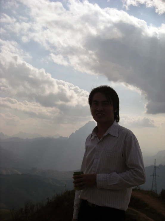 the man is enjoying a cup of coffee at the top of a mountain