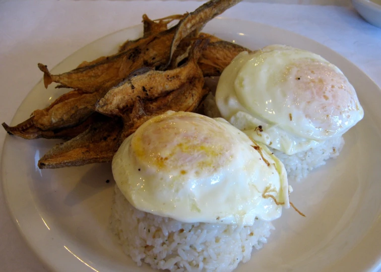 two eggs on top of rice, next to fried plantains
