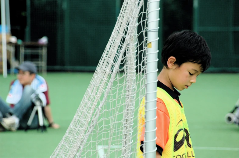 small boy looking at soccer ball in goal net