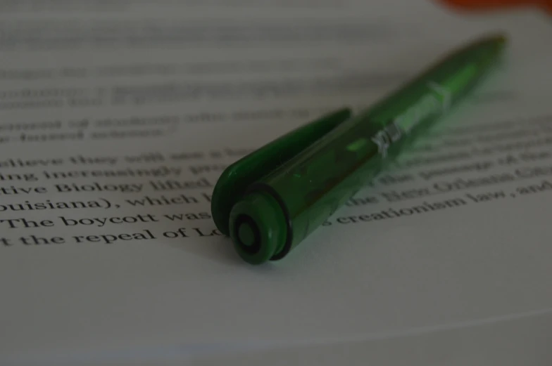 the green pen is sitting on top of an open mcript