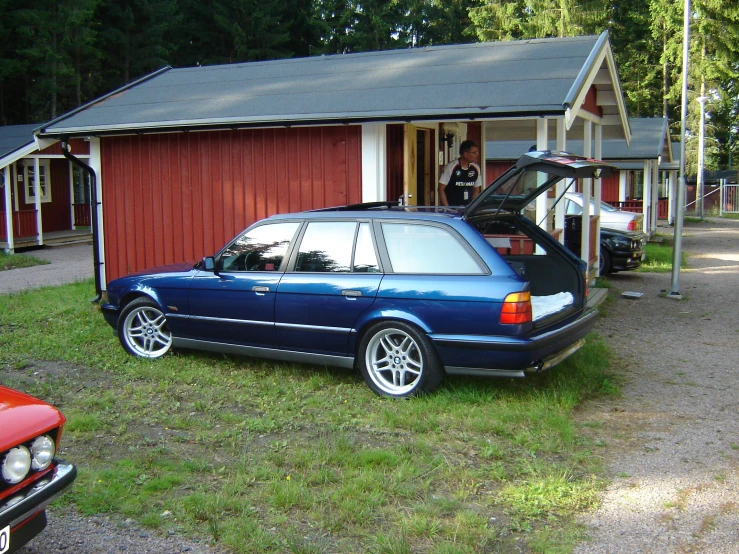 an mercedes benz estate with its doors open in front of a small house