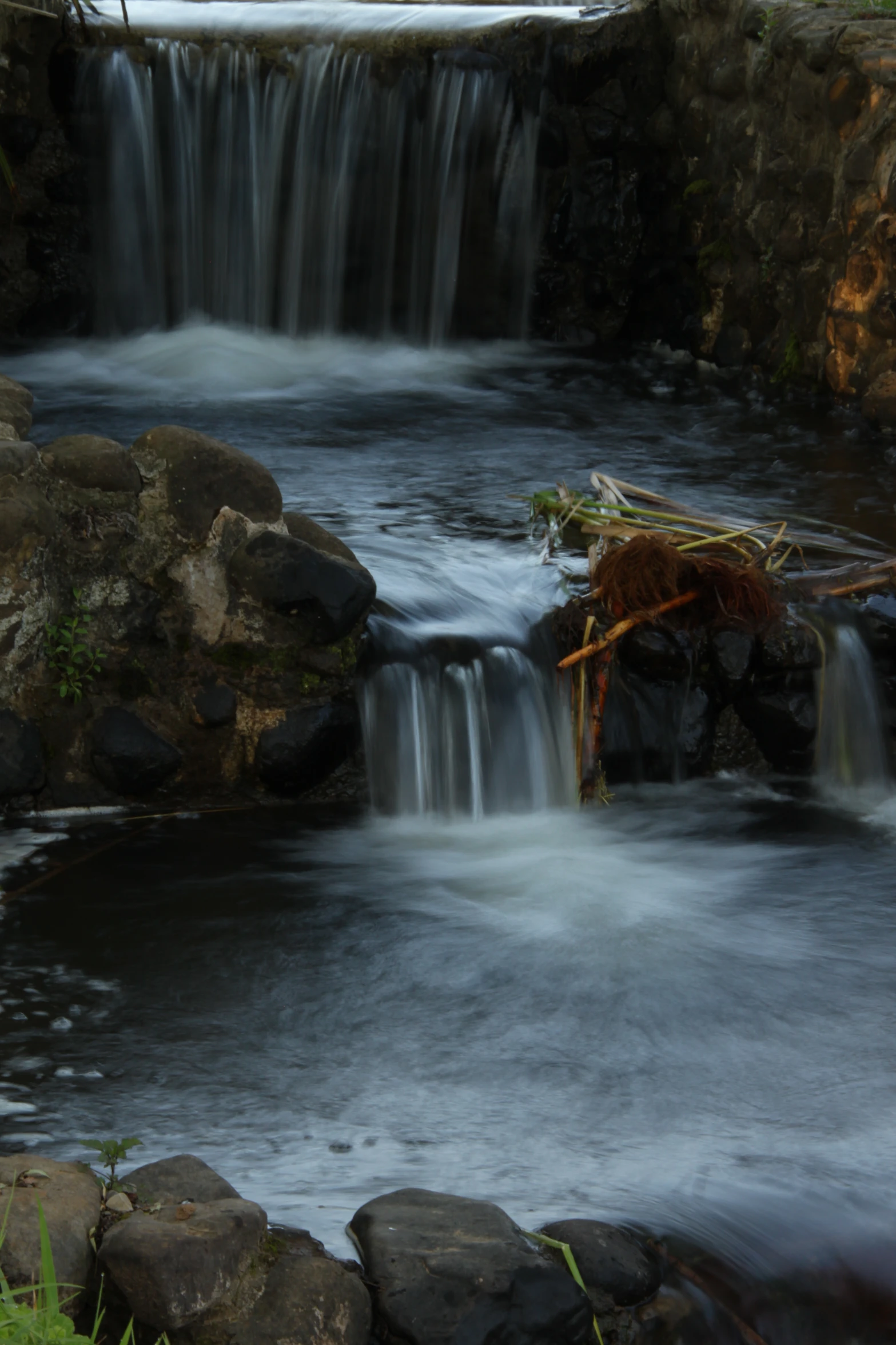 a small waterfall flowing over rocks on top of water