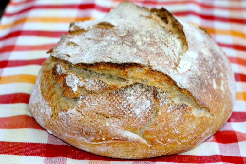 a round loaf of bread sitting on a checkered tablecloth