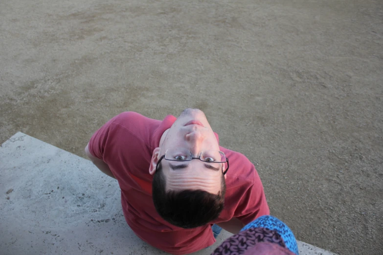 a boy with glasses sits on the ground