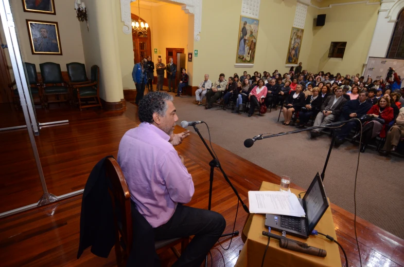 a man is speaking into a microphone next to a laptop computer