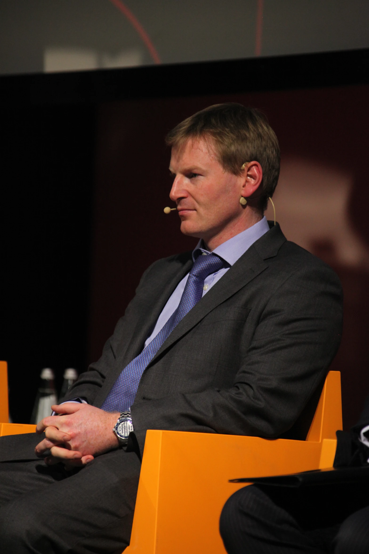 a man in a suit sits down with his hands together