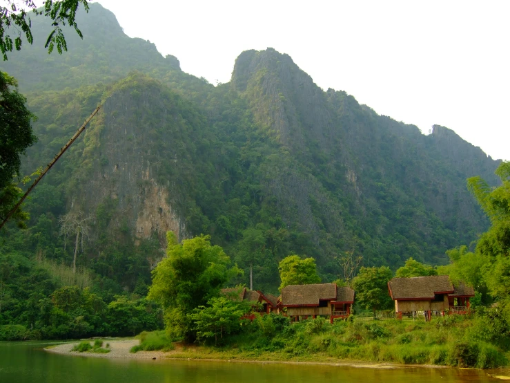 a grassy area with trees and mountains behind it