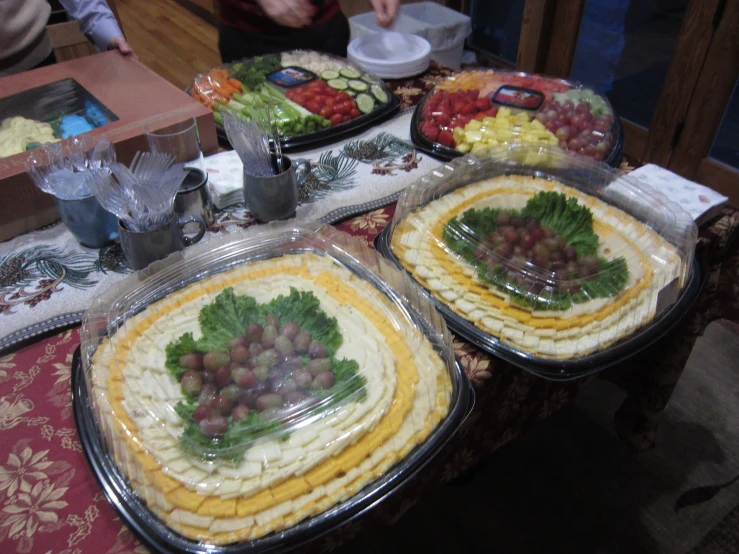 food in plastic trays on a table, with people eating at the tables in the background