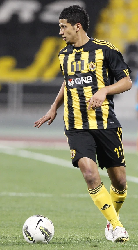 a man in black and yellow uniform kicking soccer ball