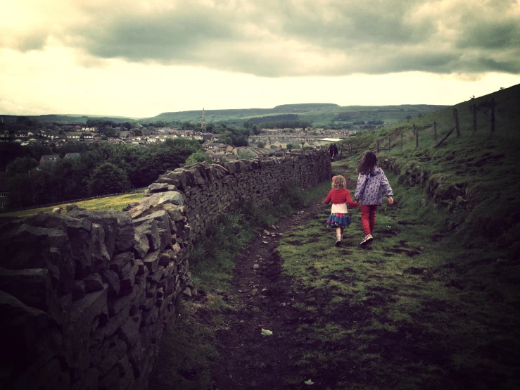 a  is carrying her little daughter as they walk up a path