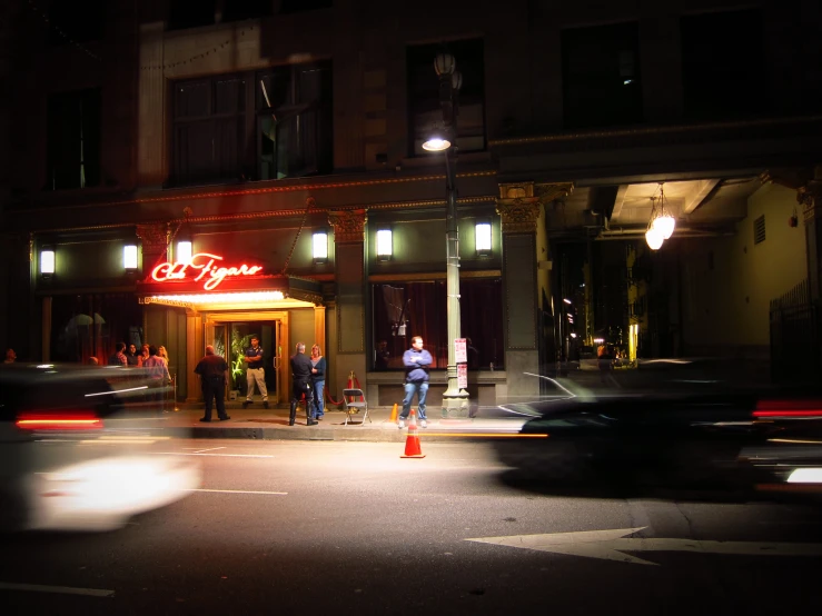 a restaurant with red neon signs and two people on the sidewalk