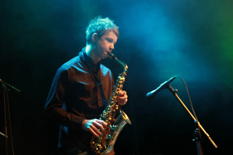 a person with a saxophone standing near a microphone