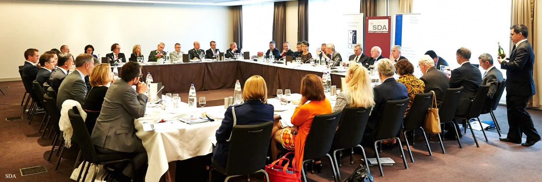 people are seated at round tables with microphones