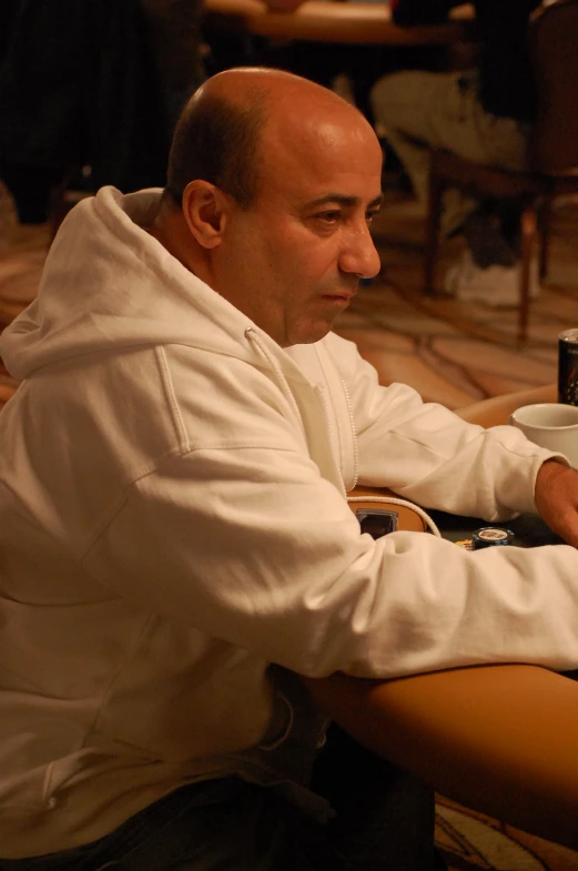 a man sitting at a table looking at soing while holding a mug