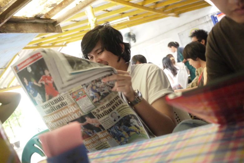 a boy is sitting down reading a newspaper