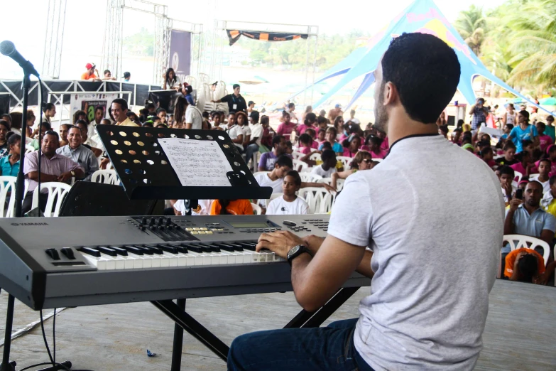 a man sitting at an electronic keyboard playing music