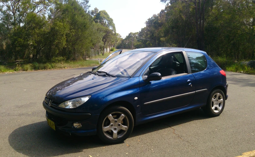 a small blue car on the street and trees