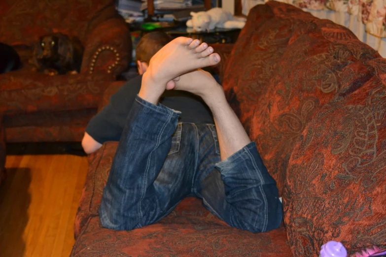 a young man with his feet up in a reclining position on the couch