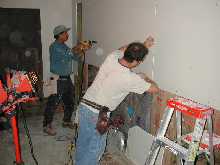 two men working on the wall in a house