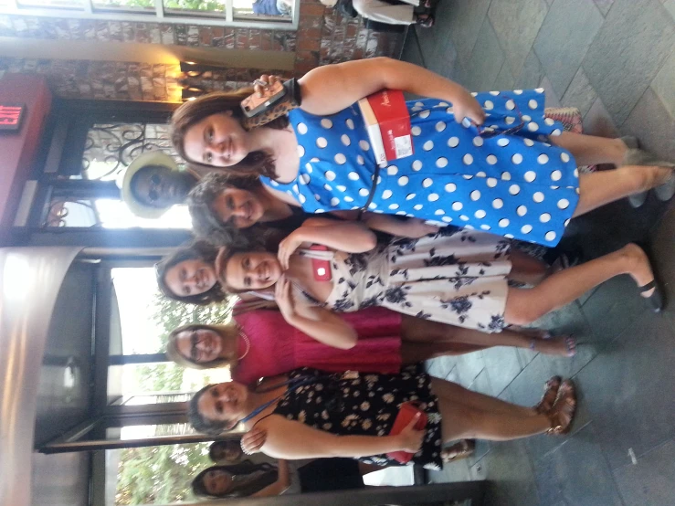 a group of woman in dresses smiling and taking pictures