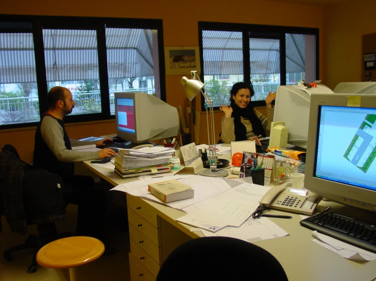 two people in a room with computer screens and papers