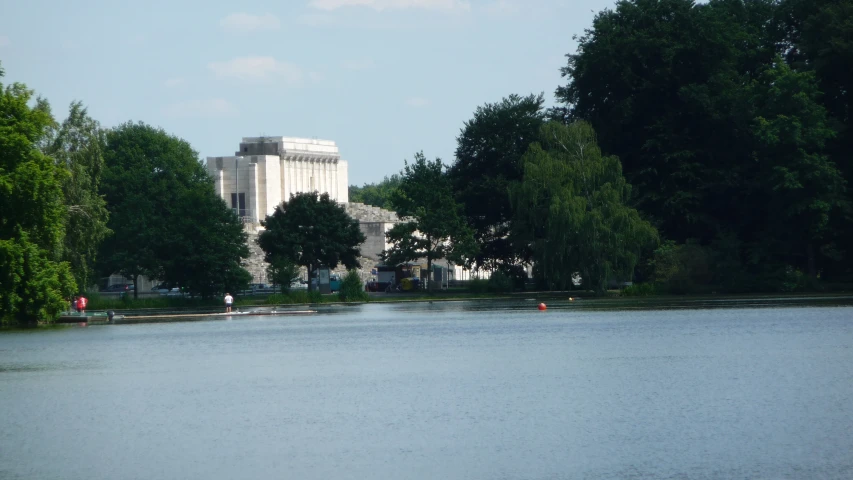 a building near the water with trees lining the sides