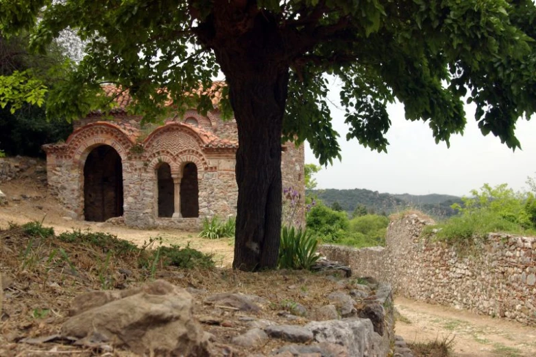 a stone building and a tree with leaves on it