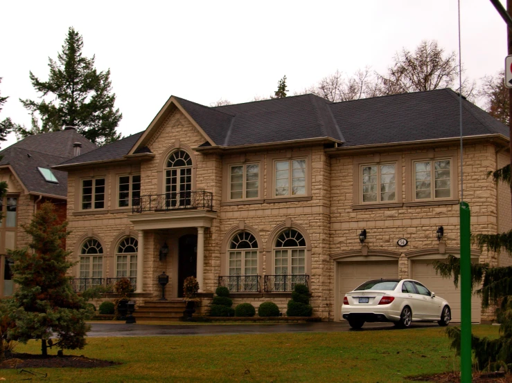 a car is parked in front of a large, beautiful house