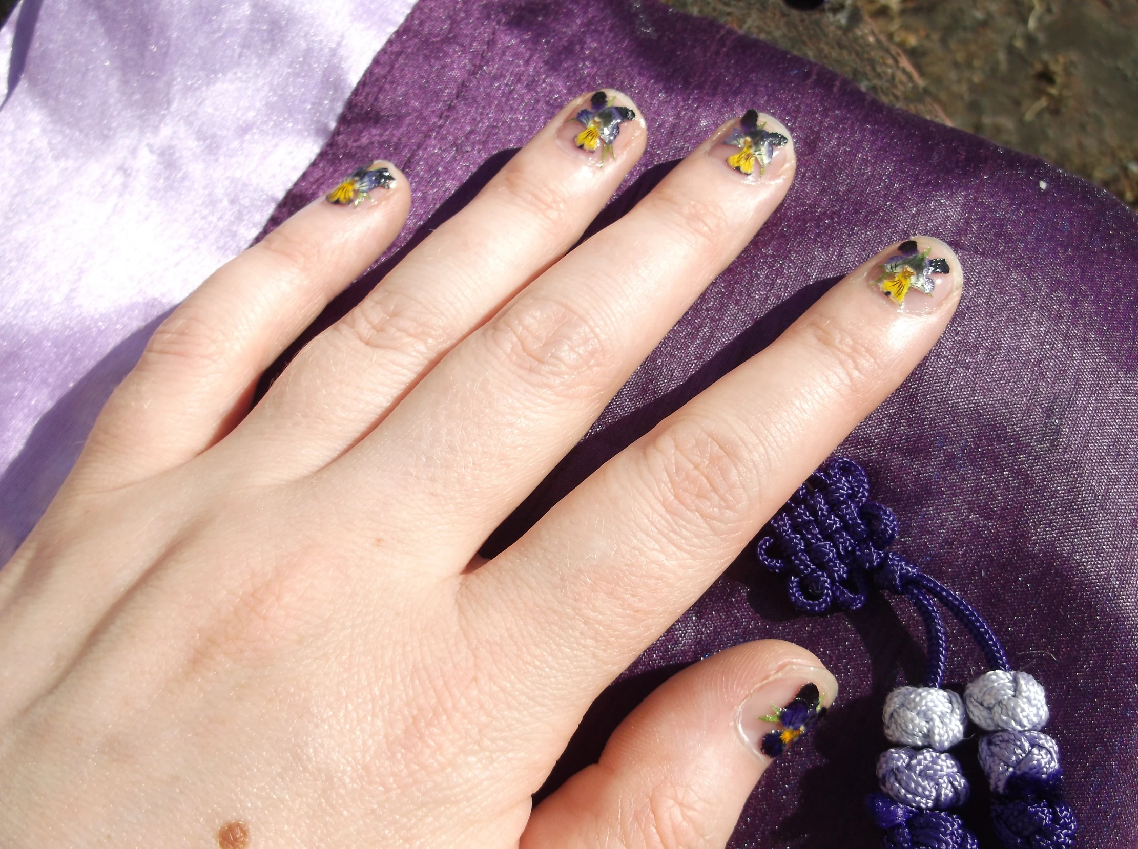 female with bright designs on her nails on purple cloth