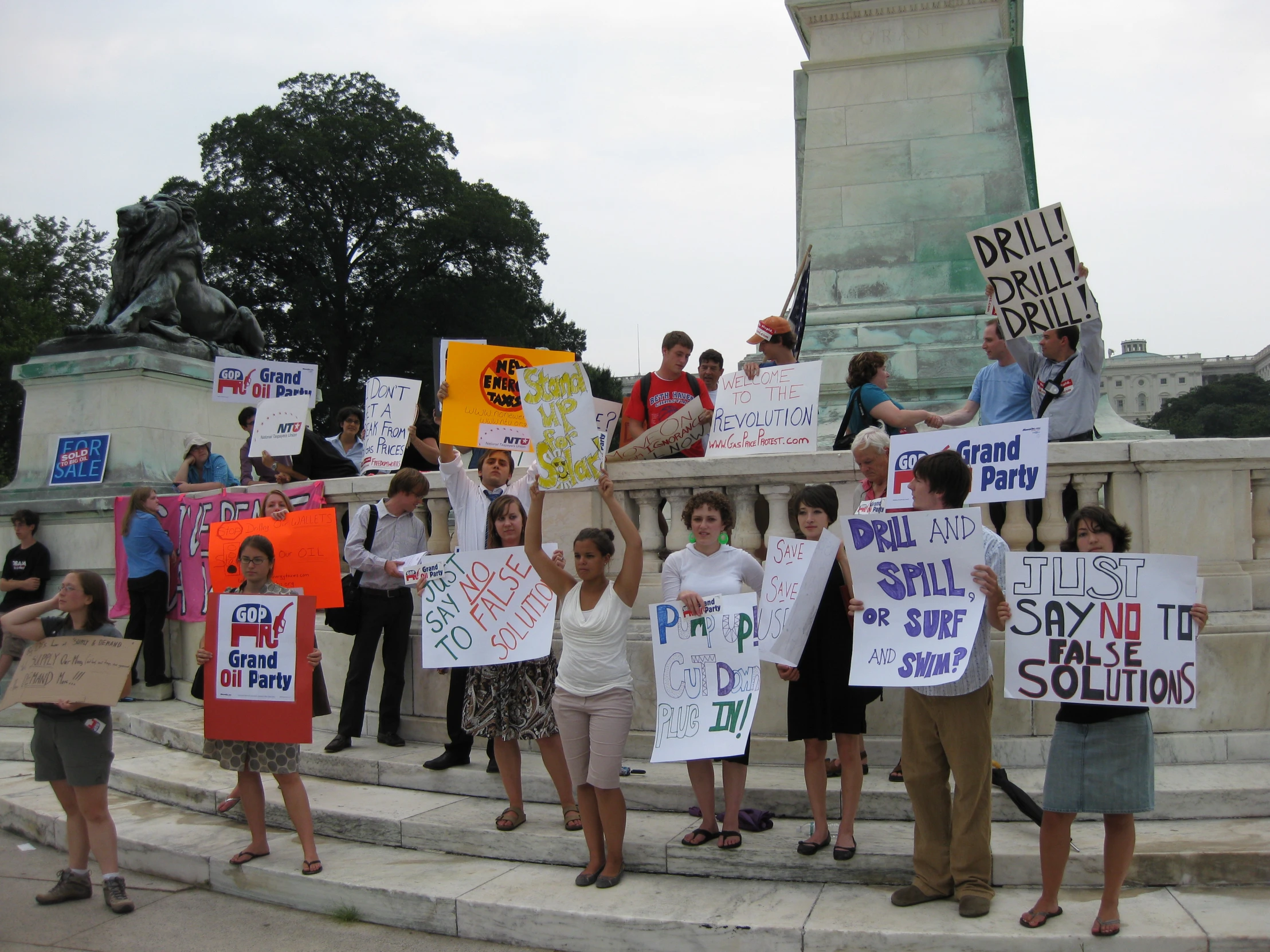 many people with protest signs near a monument