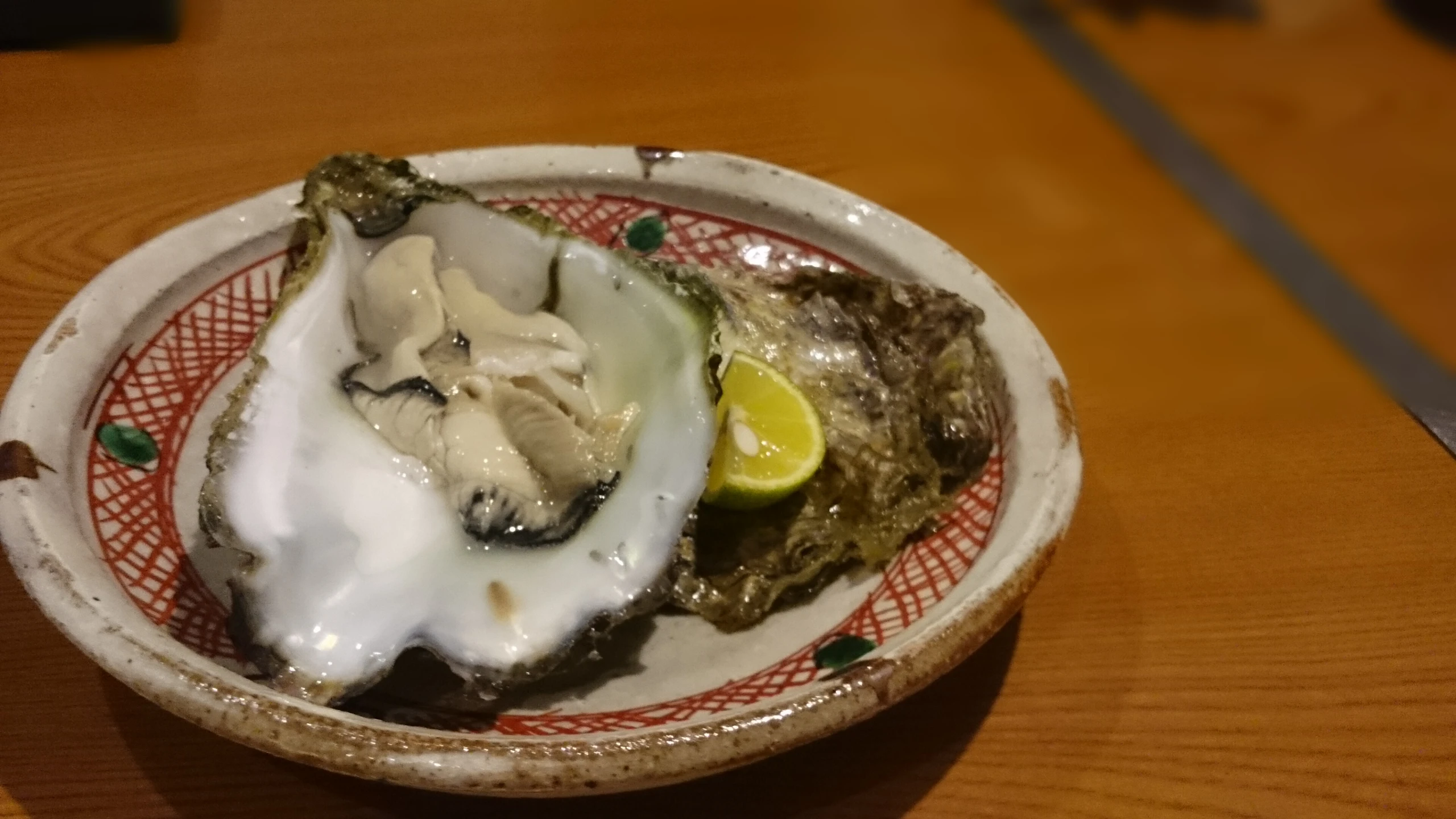 an oyster is on the side of a white and red plate