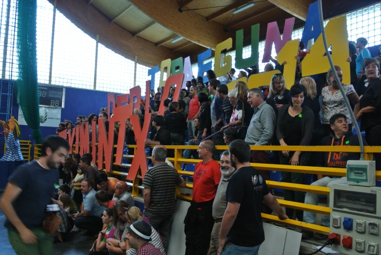 a crowd of people sitting in a room while someone holds up a microphone