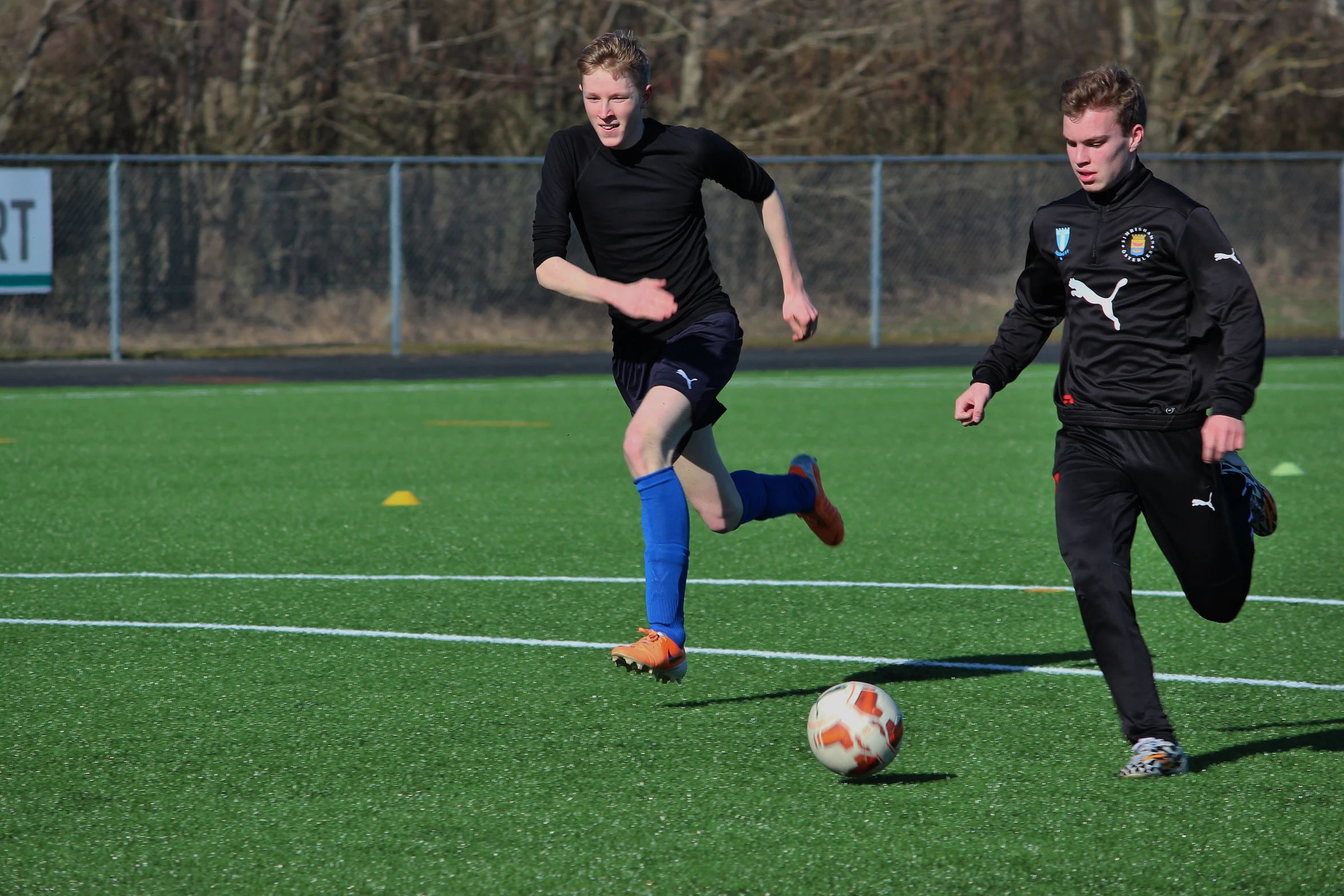 the two soccer players are chasing the ball