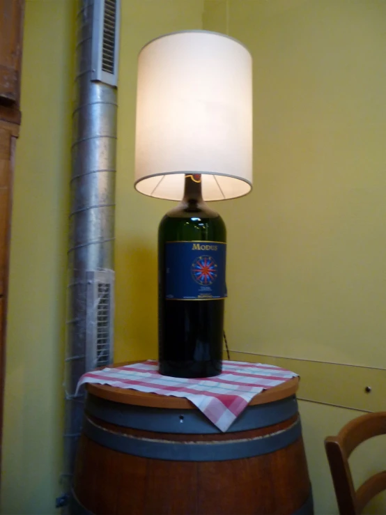a bottle on a table lamp near a wine barrel