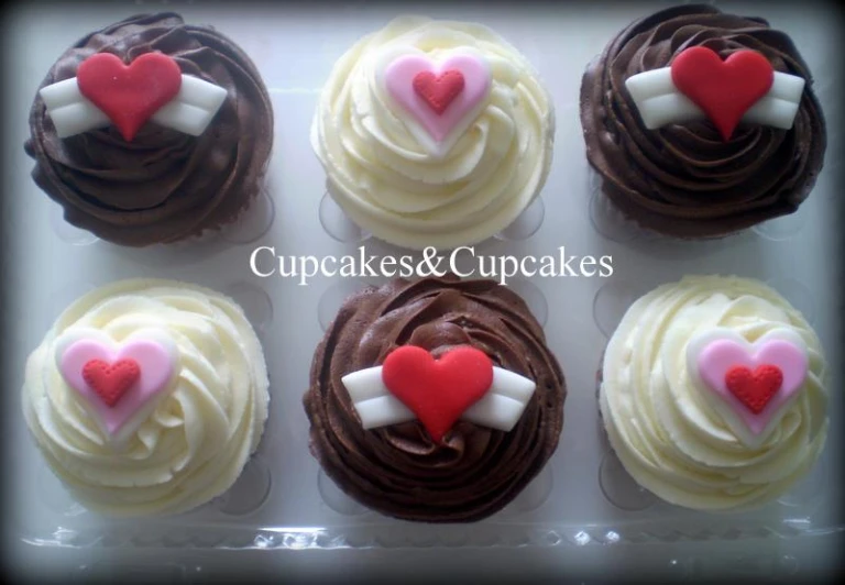 cupcakes are in a box with heart decorations