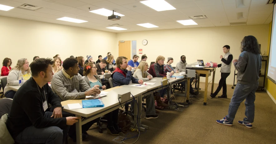 many people sit at desks and watch on the screen