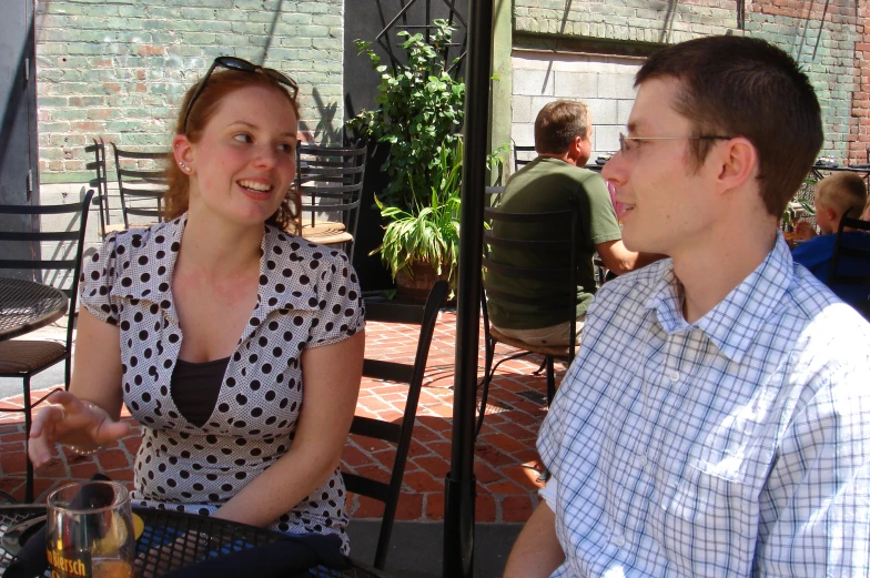 two people are sitting outside under an umbrella