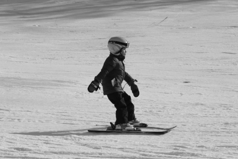 a little boy with helmet and goggles on a snow board