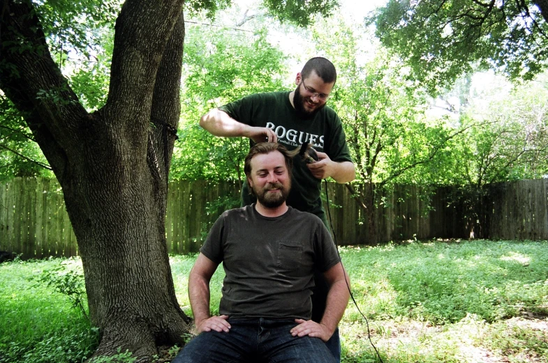 a man sitting on his dad's lap as he combs his hair
